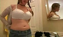 Seorang remaja amatir dengan payudara besar menggoda dirinya dengan bra di kamar mandi